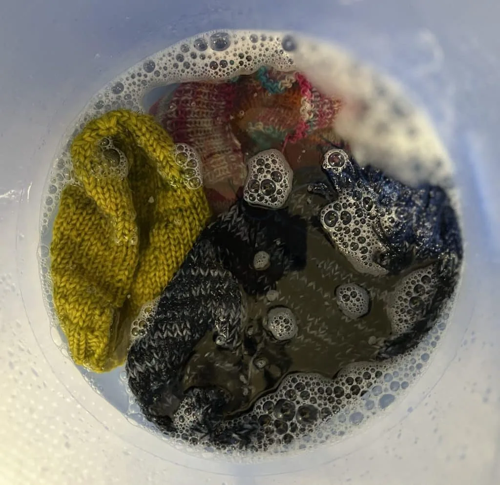 Bucket with three hats soaking in sudsy water