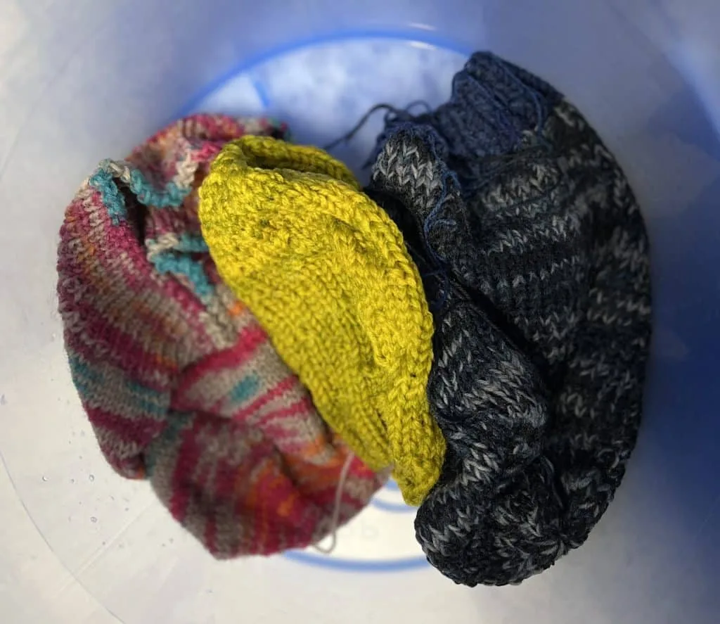 Three hats in a bucket with most water removed.