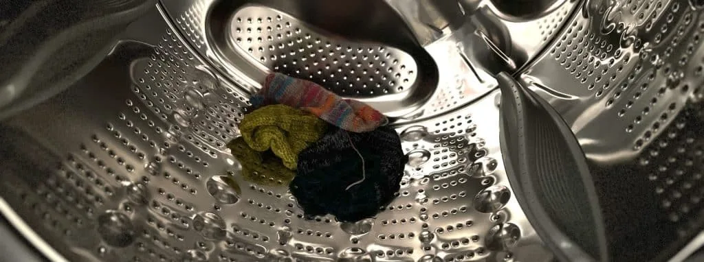Three knitted hats that have been added to the washing machine.