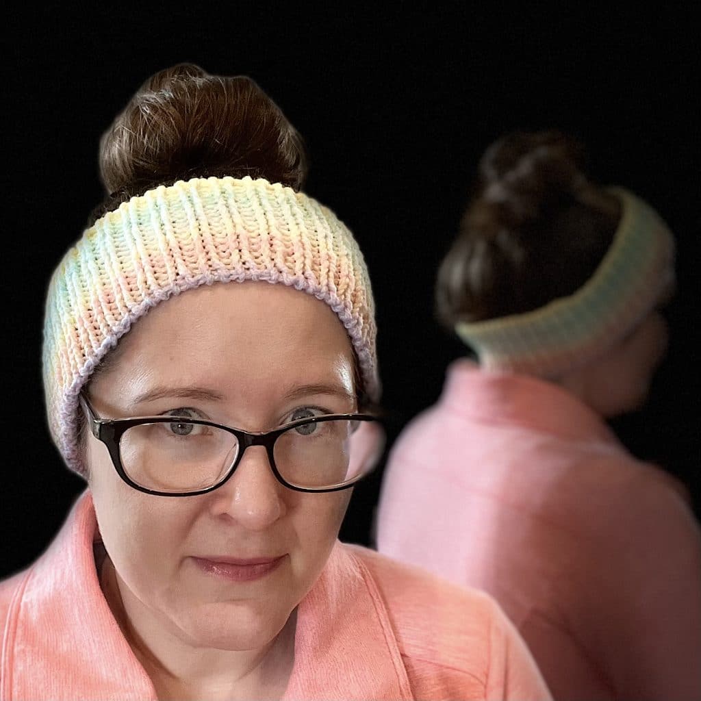 Endless Love Spell Ear Warmer Pattern Woman with dark brown hair in a messy bun wearing a ribbed ear warmer with gradient colors.