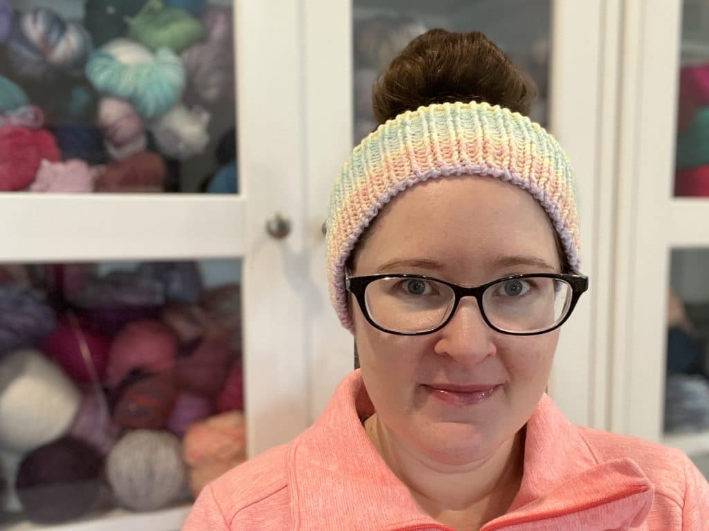 Endless Love Spell Ear Warmer Pattern Woman with dark brown hair in a messy bun wearing a ribbed ear warmer with gradient colors.